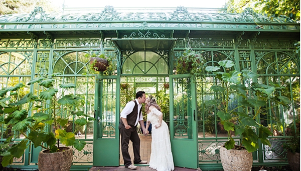 Couple in wedding attire kiss in front of solarium