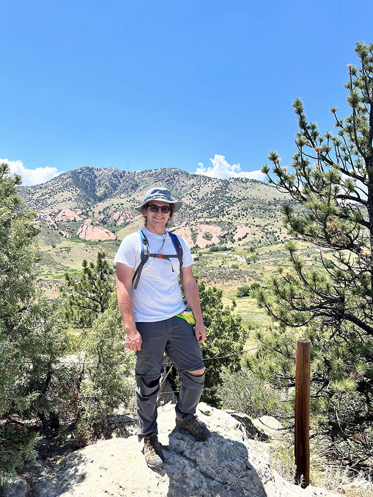 Man with mountain view behind him. 