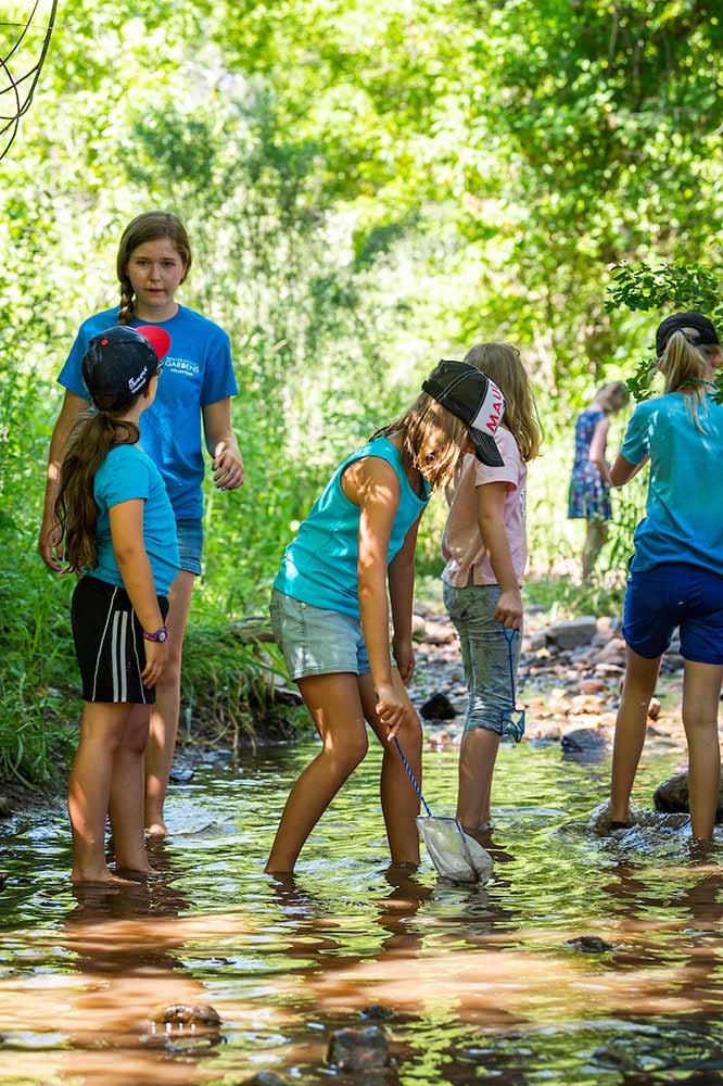 Adult and children pointing at water in a river at Chatfield Farms