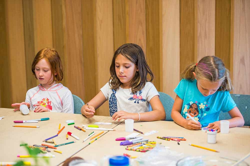 Three girls doing crafts for Scout and community group programs