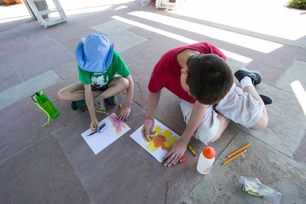 Two children sitting on the ground inside doing crafts.