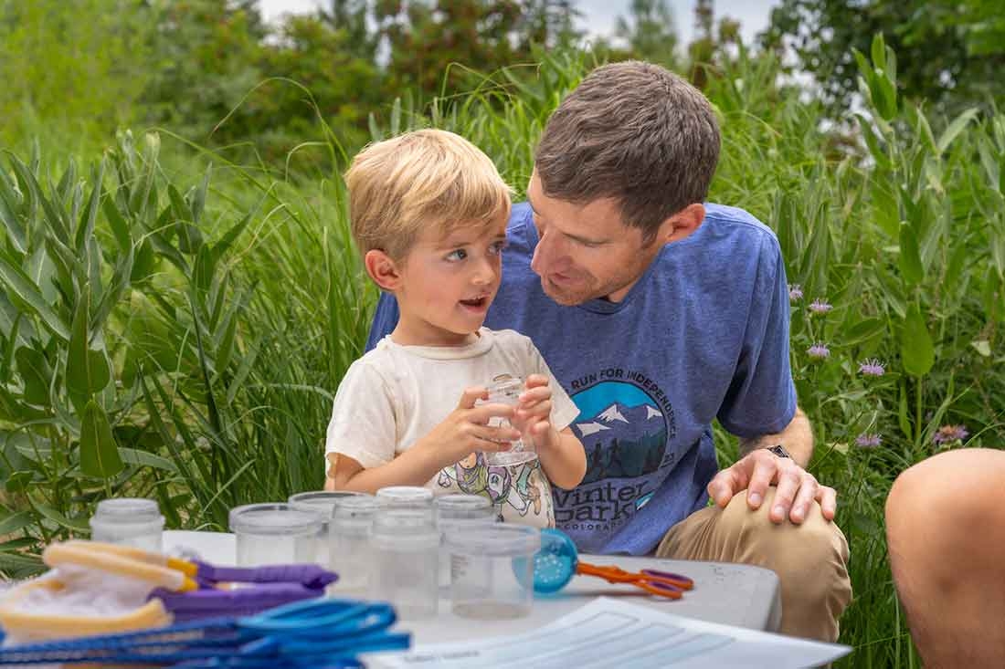 An adult and a child holding a plastic container.