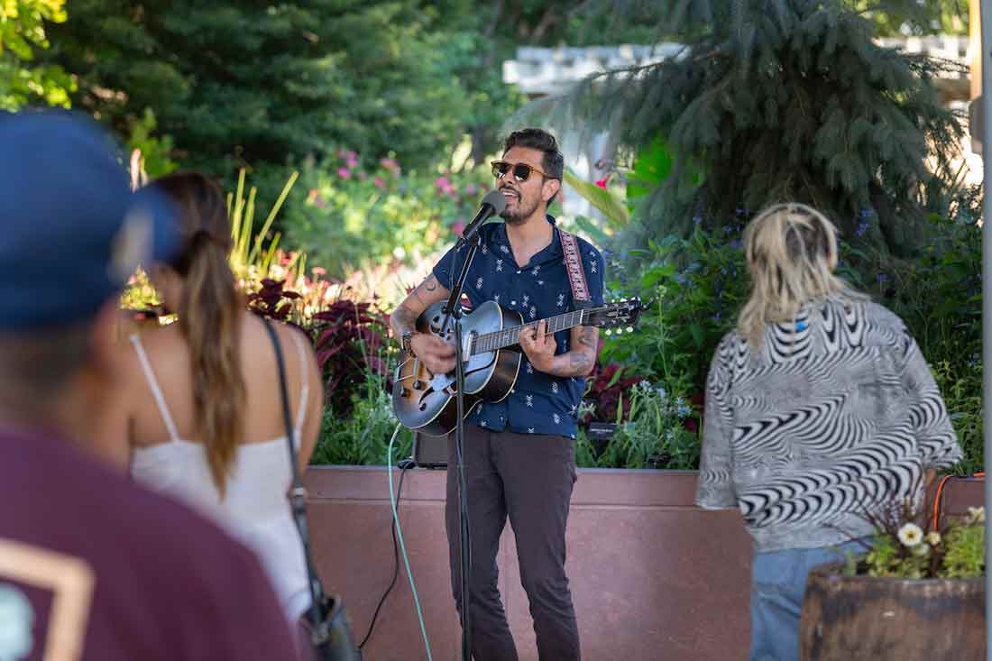 Person playing a guitar during Evenings al Fresco