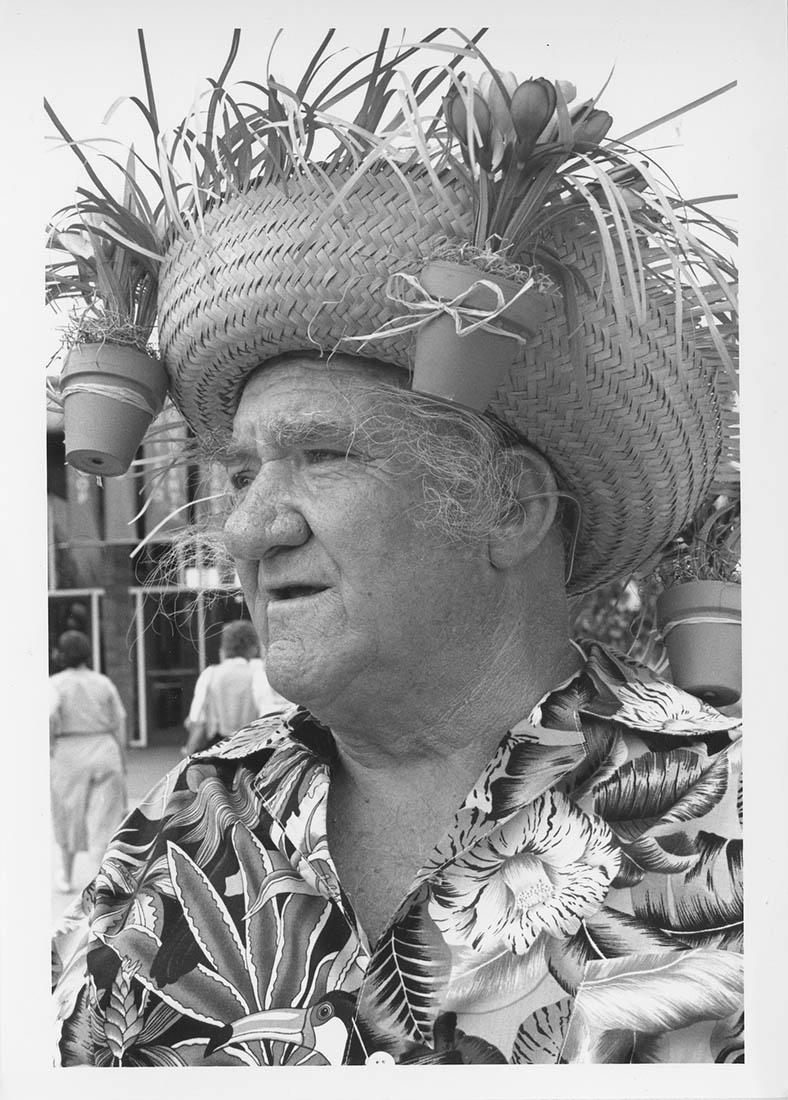 black and white photo man in straw hat with mini plant pots on it