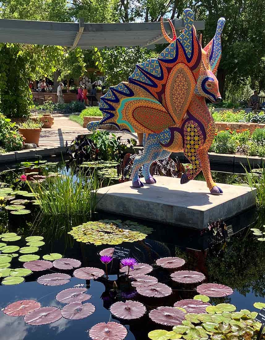 Waterlilies in a pond with a large colorful sculpture sitting on a pedestal