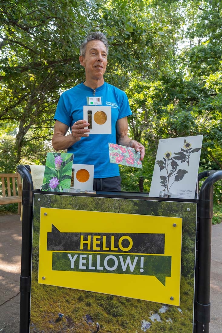 Man standing behind a cart with the words Hello Yellow on the front. He is holding a card with a yellow circle.