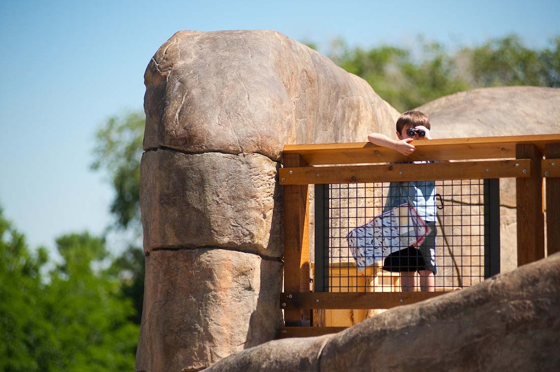 Boy standing on bridge and holding binoculars
