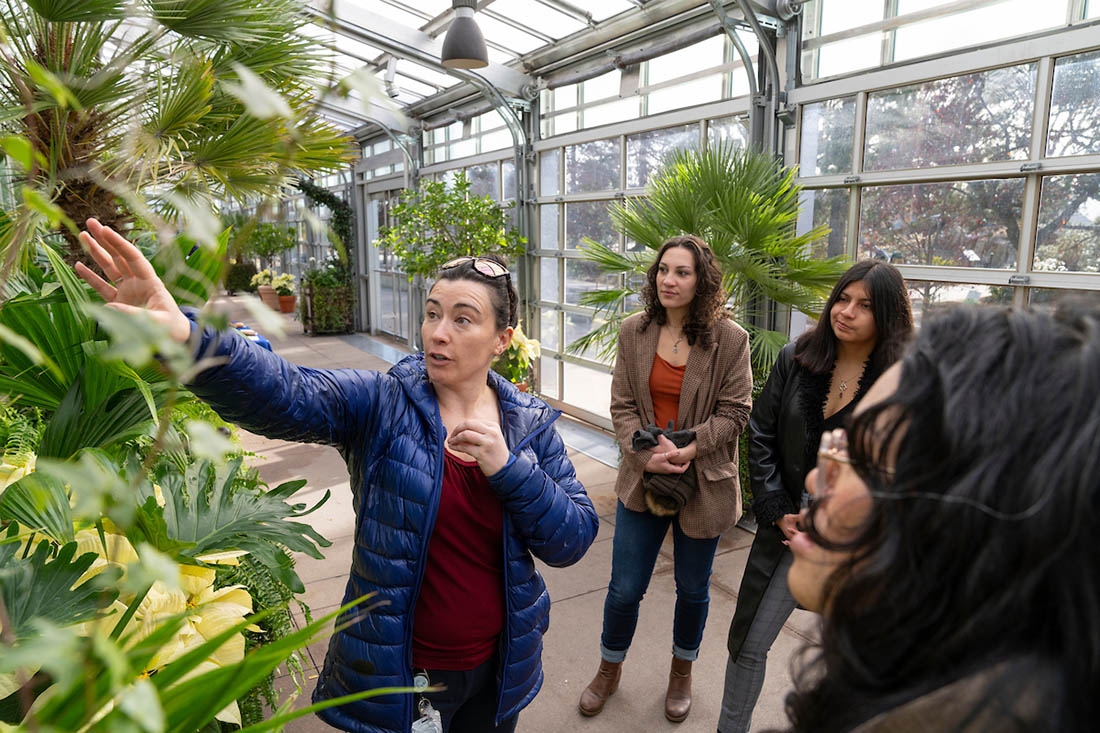 A tour leader points at a plant while others look on