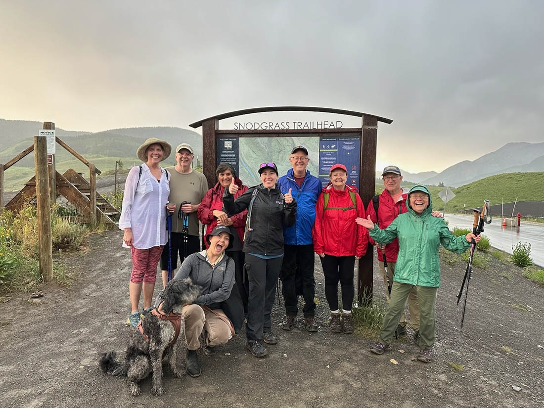 A hiking group poses in front of a trailhead