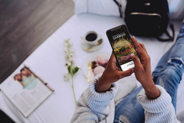 Hands holding smart phone with Bloomberg Connects app displayed on screen
